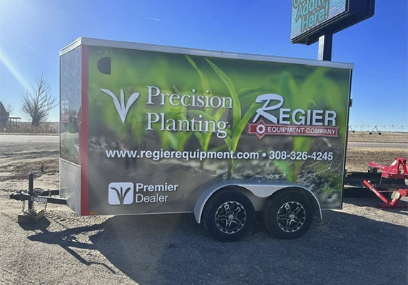 Equipment Company trailer wrapped in Precision Planting branding, promoting premier dealer status and services.