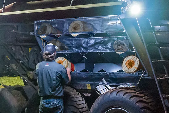 Technician loading twine spools into a baler at night using AGCO equipment – ensuring reliability and uptime during harvest.