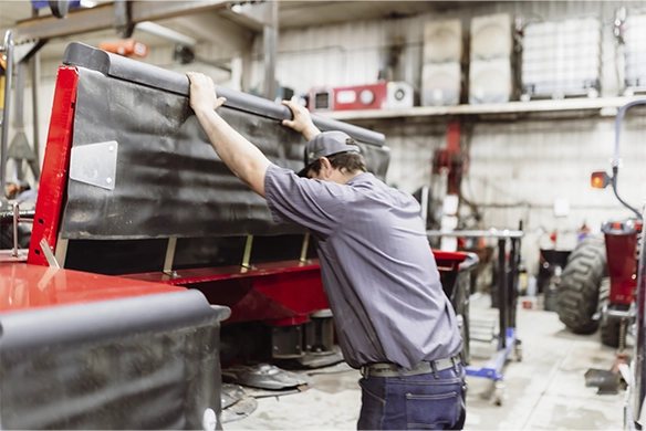 Regier Equipment service team preparing hay equipment for repairs in dealership's indoor bay